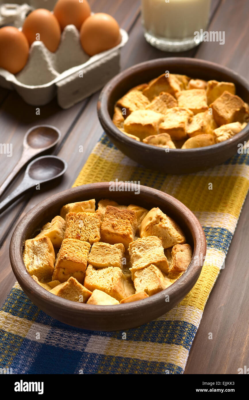 Two rustic bowls of bread pudding made of diced stale bread, milk, egg, cinnamon, sugar and butter Stock Photo