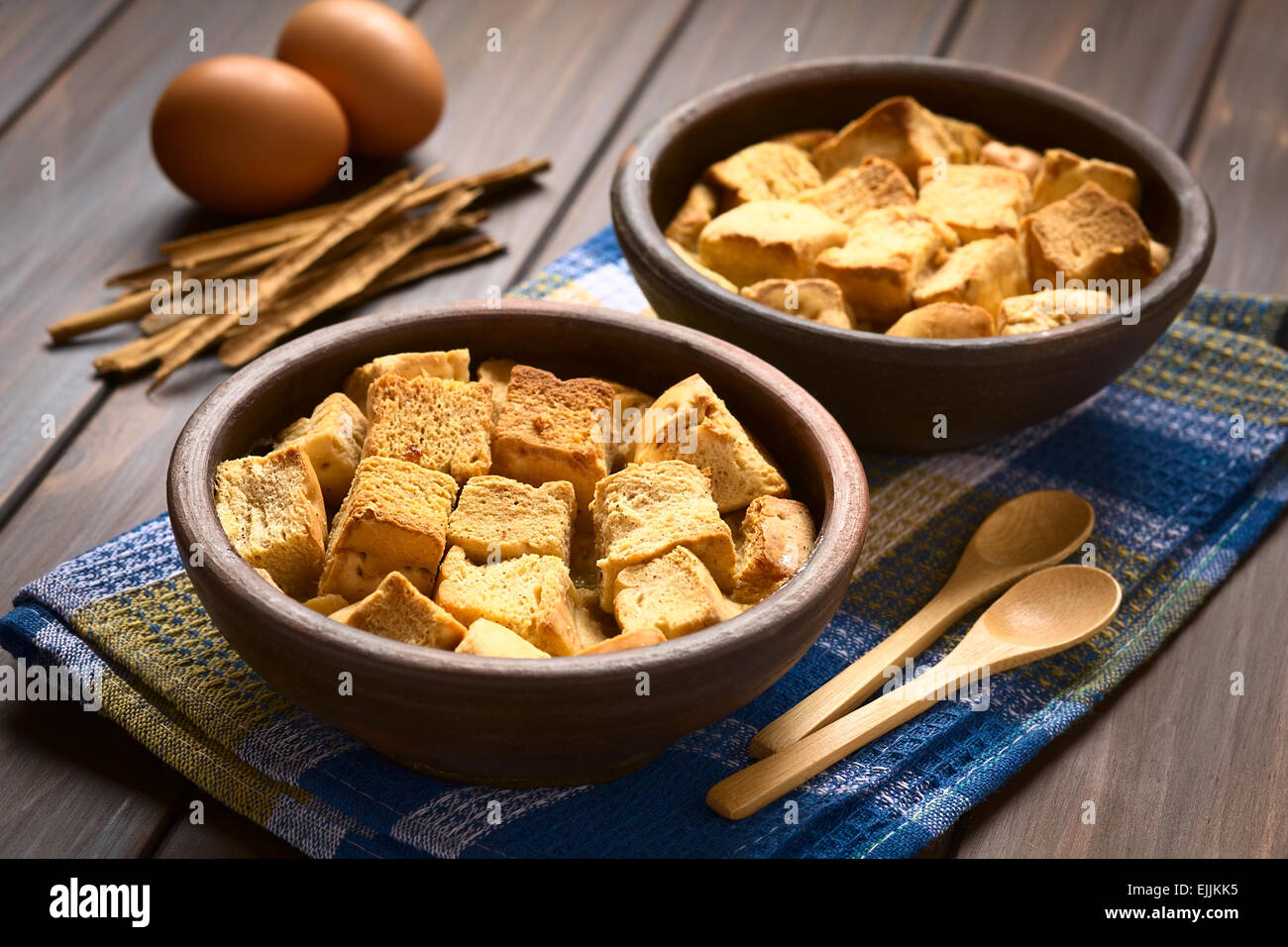 Two rustic bowls of bread pudding made of diced stale bread, milk, egg, cinnamon, sugar and butter Stock Photo