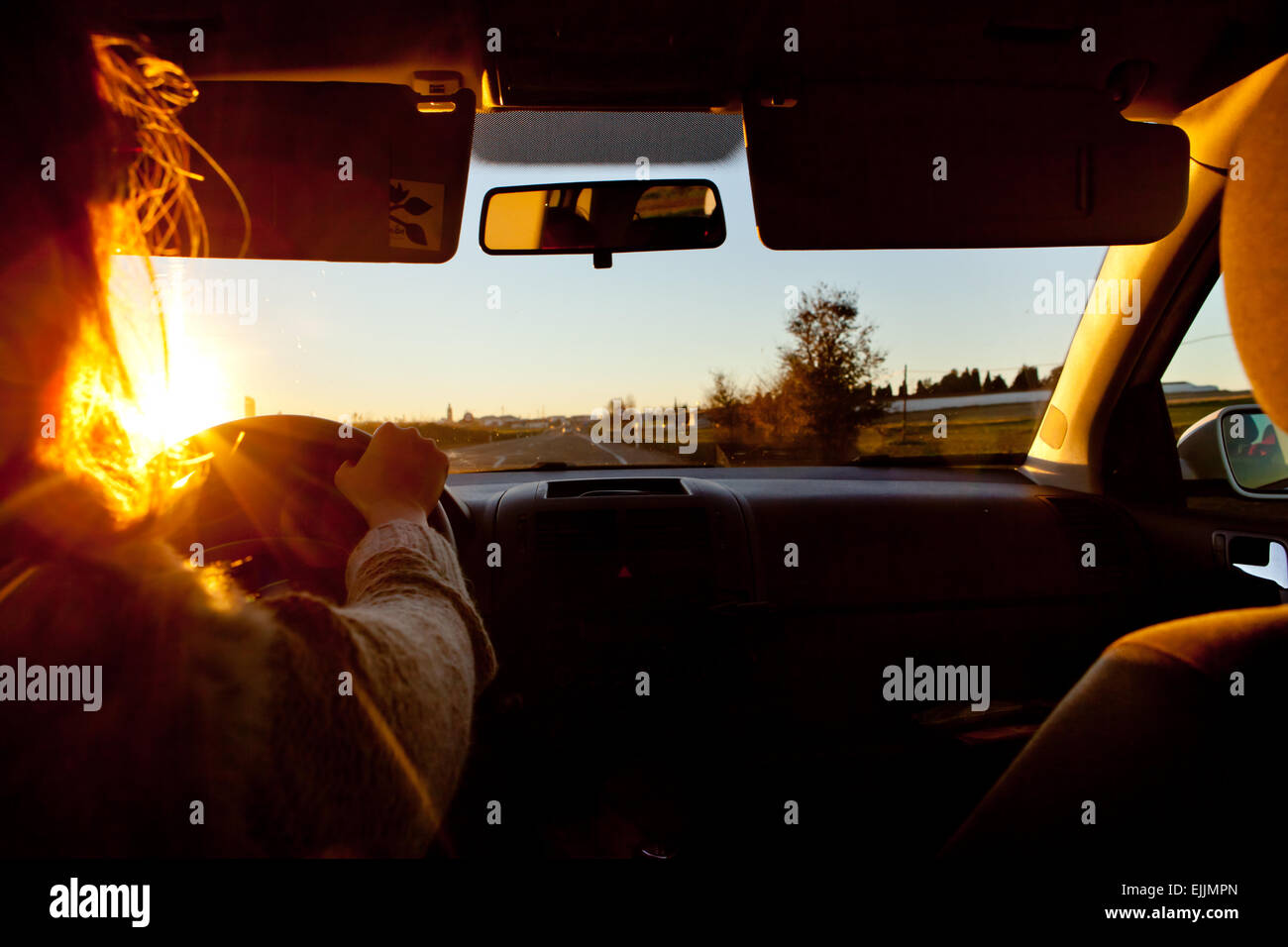 A woman driving at sunset. Trouble of vision in this day hour Stock Photo