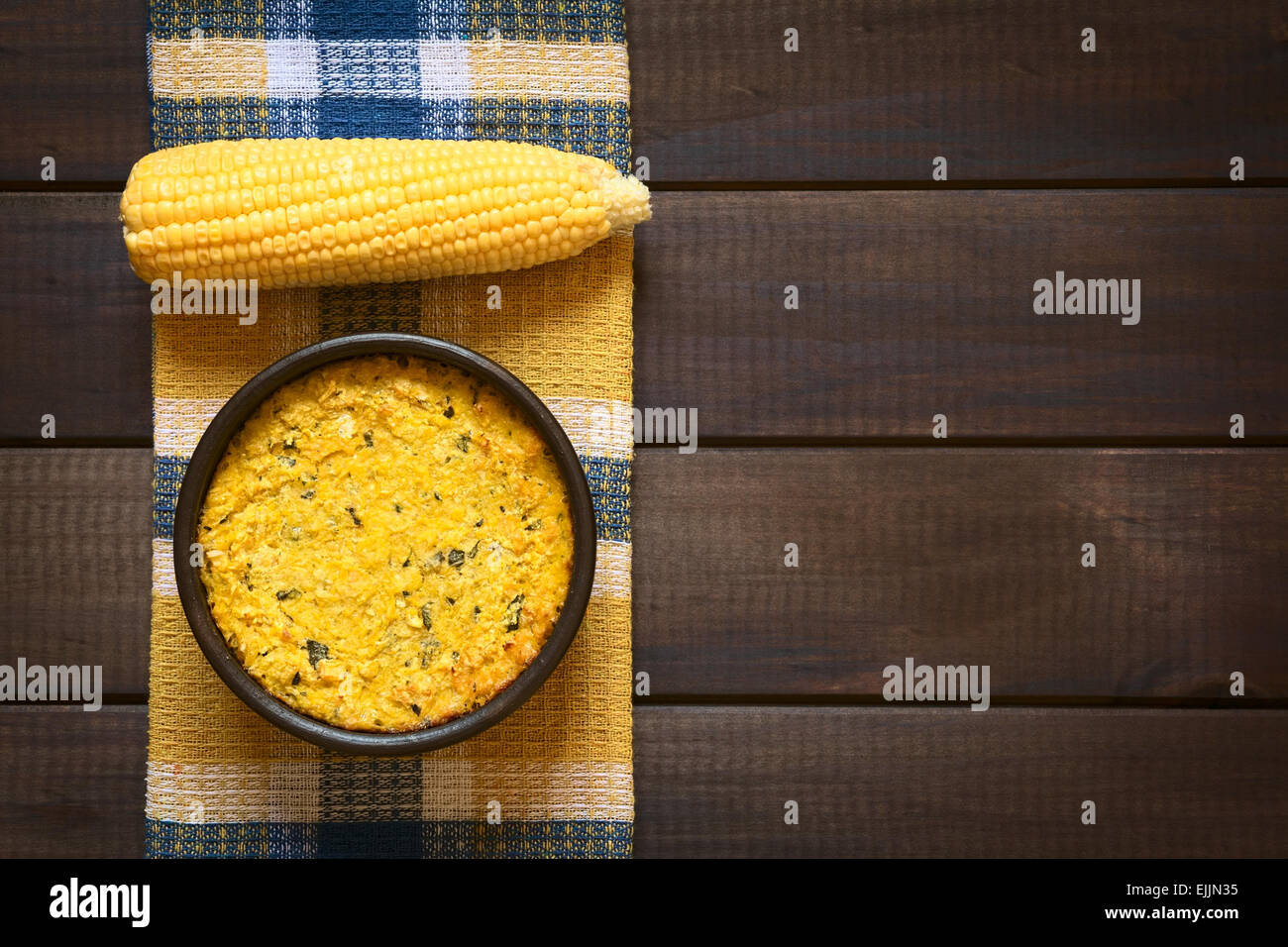 Overhead shot of traditional Chilean corn pie called Pastel de Choclo served in bowl, photographed on dark wood Stock Photo