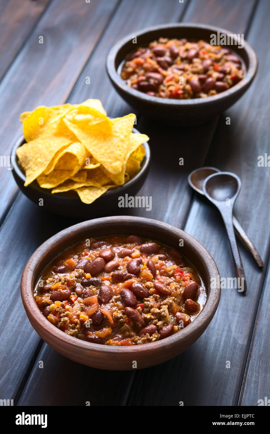 Two rustic bowls of chili con carne with tortilla chips in the back, photographed with natural light (Selective Focus) Stock Photo