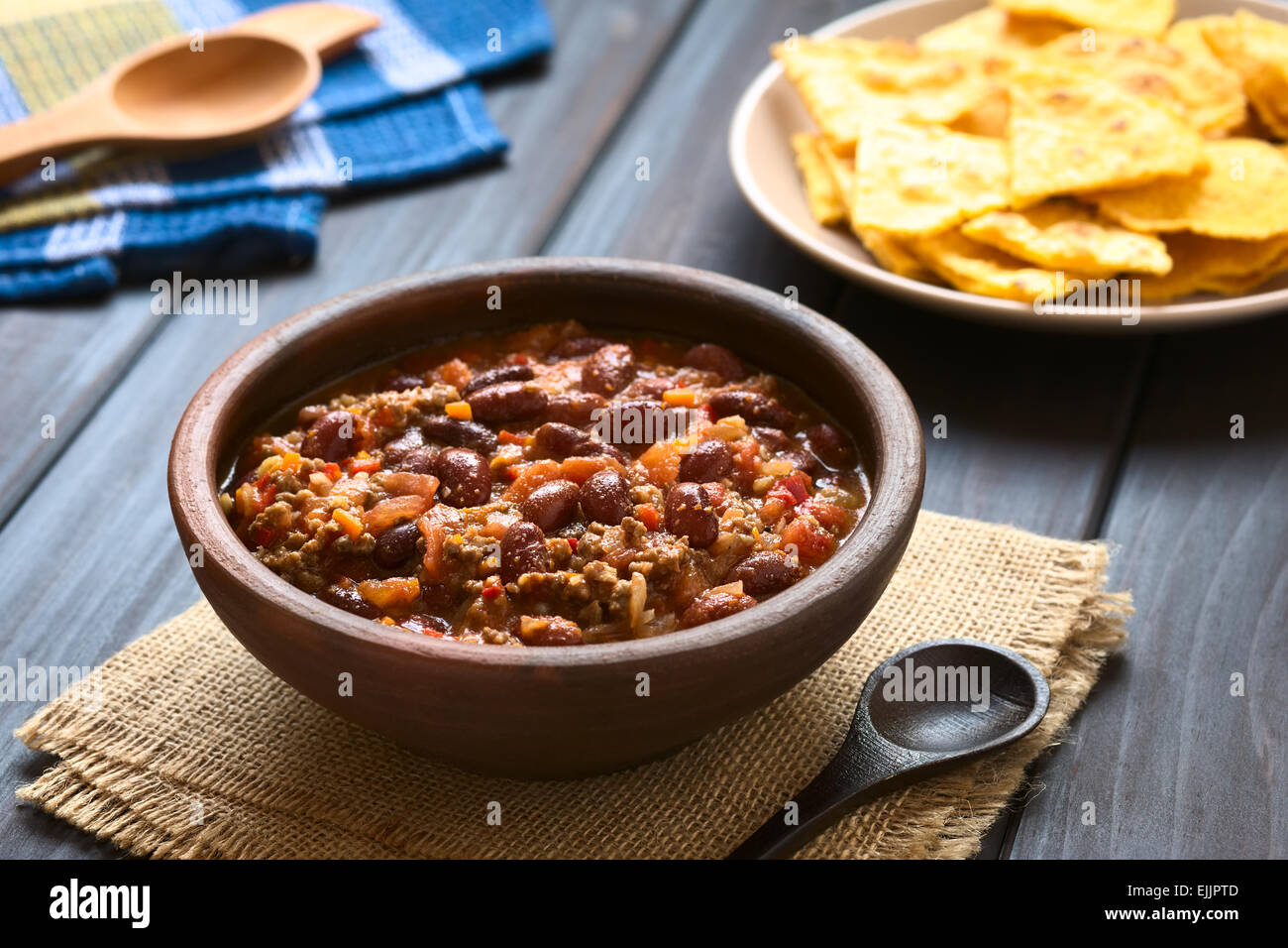 Rustic bowl of chili con carne with homemade tortilla chips in the back, photographed with natural light (Selective Focus) Stock Photo