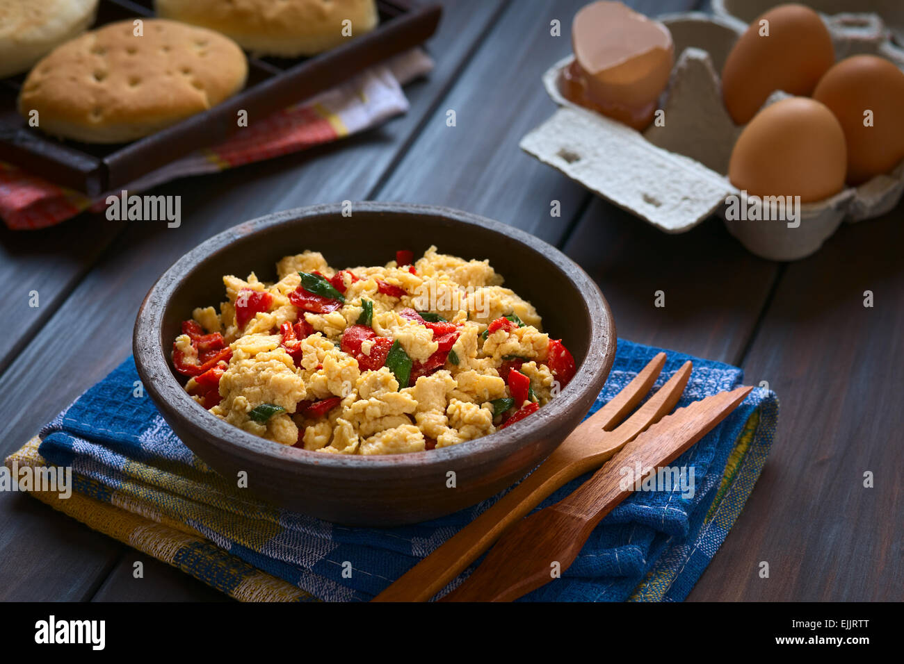 Scrambled eggs made with red bell pepper and green onion in rustic bowl