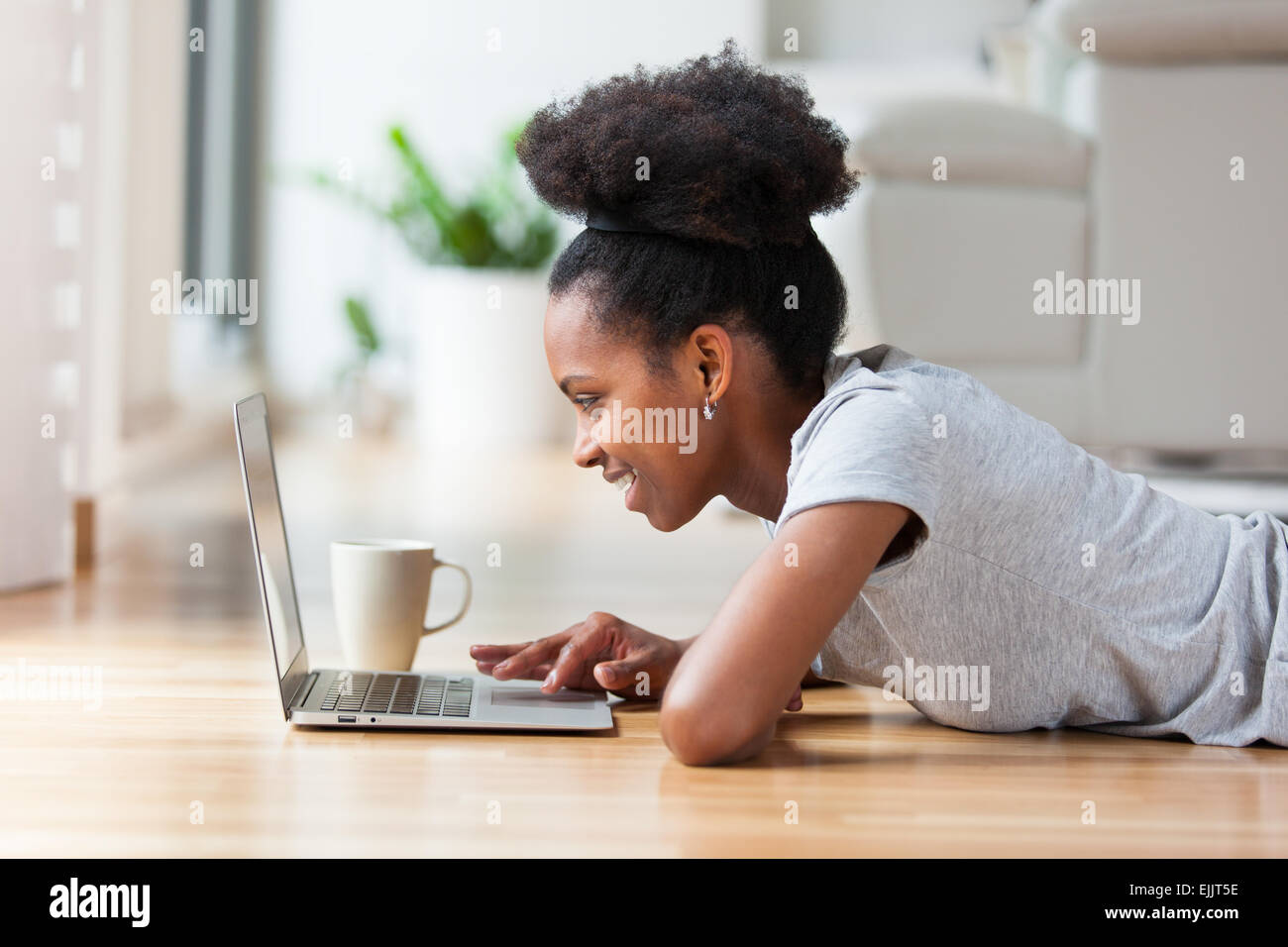 African American woman using a laptop in her living room - Black people ...