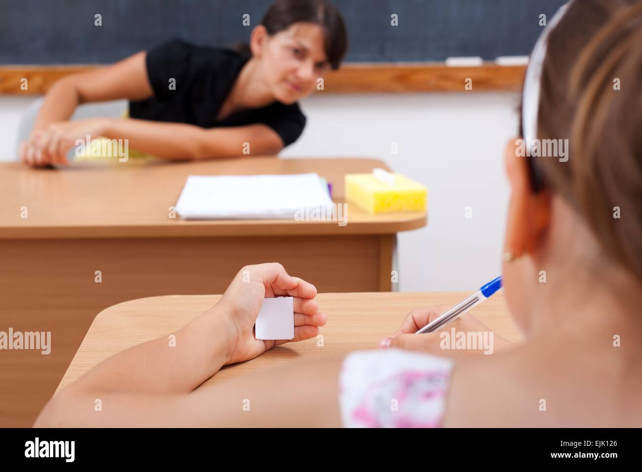 Student cheating while writing test, teacher is looking at her Stock Photo