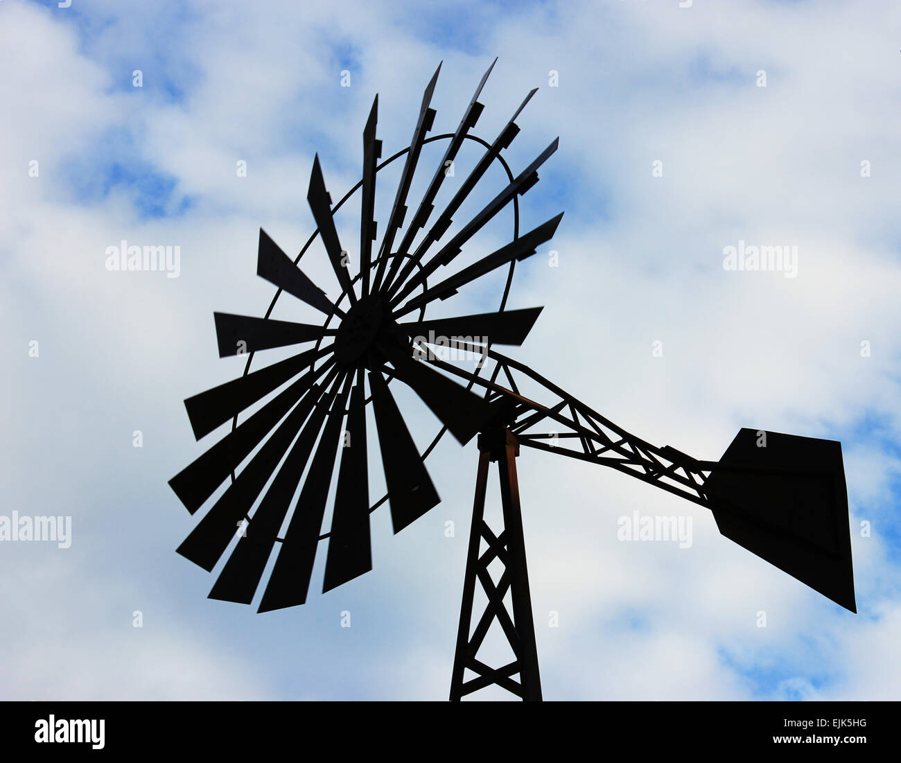 OLd water pumping windmill. Windmill water tower on sky background. Dark silhouette of farm