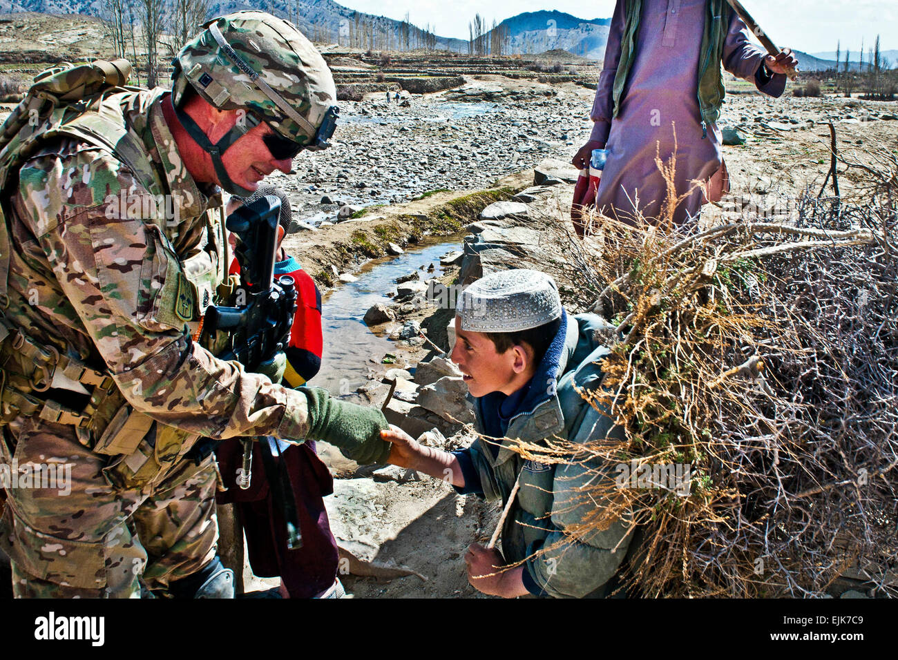 Command Sgt. Maj. Michael Boom, 172nd Infantry Brigade, greets an Afghan boy while on a foot patrol to inspect construction progress of Afghan Local Police checkpoints in the Marzak Basin. Marzak has historically been a stronghold for the insurgency over the past decade until Company A, 2nd Battalion, 28th Infantry Regiment, Task Force 3-66th, took advantage of the winter months to establish a local police force and secure the village from foreign fighters. Stock Photo