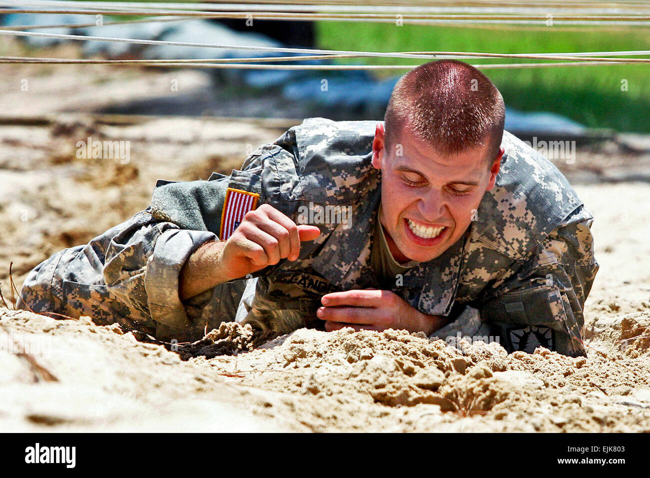 Army Sgt. Matthew Howard crawls over sand under ropes at the Warrior ...