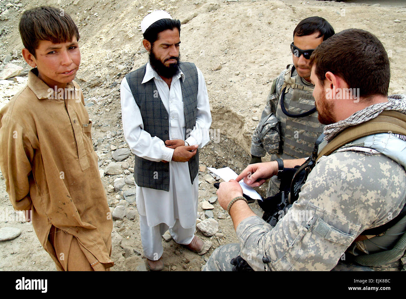 U.S. Army Staff Sgt. Artez Briseno, right, speaks with Mohammad Eqbal,   left center, Gar Sagi village elder, about treatment for Ashqmana Gulab, left, Oct. 29, 2009, in Kunar province, Afghanistan. Ashqmana can't lift his right arm more than six inches because a dislocated shoulder from a fall didn't heal properly. Briseno did an initial   assessment of the boy and gave the elder an authorization slip.  Tech. Sgt. Brian Boisvert Stock Photo