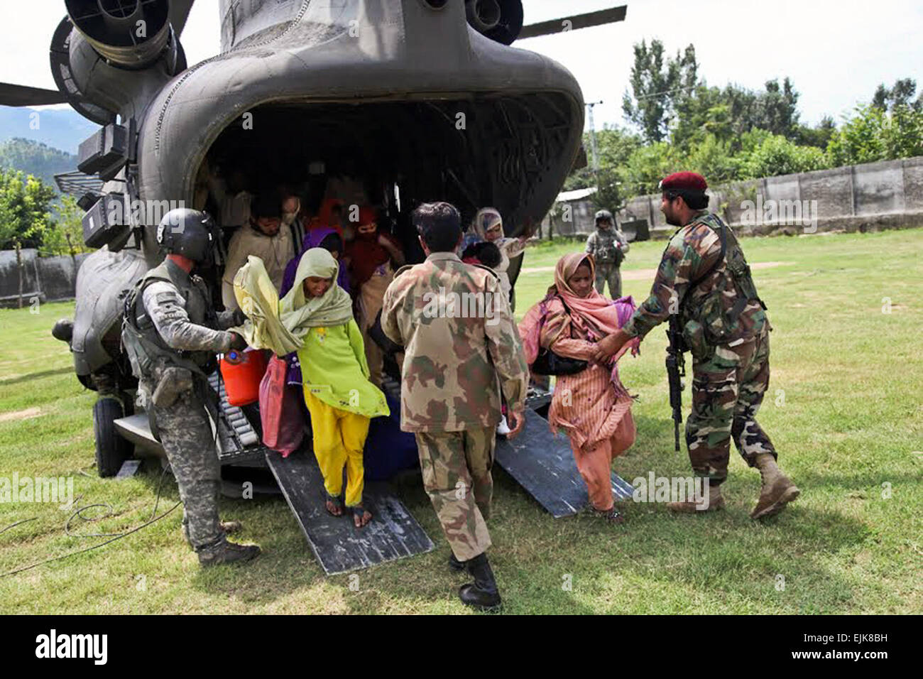 A U.S. Army soldier and Pakistani troops help Pakistani residents as they disembark from a U.S. Army helicopter in Khwazahkela, Pakistan, as part of relief efforts to help flood victims, Aug. 5, 2010. Recent heavy rains forced thousands of residents to flee rising flood waters. U.S. forces have partnered with the Pakistani military to coordinate evacuation and relief efforts.  Staff Sgt. Horace Murray Stock Photo