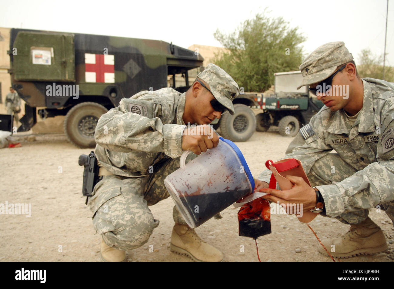 U.S. Army Sgt. Joel Ruiz, left, and Spc. Osniel Viera, both from the 82nd Sustainment Brigade out of Camp Adder, Iraq, pour fake blood into an intravenous bag during a combat casualty treatment course at Camp Mitica, Iraq, Sept. 11, 2007, for Iraqi police officers from the An Nasiriyah Tactical Support Unit.  Master Sgt. Robert Valenca Released Stock Photo