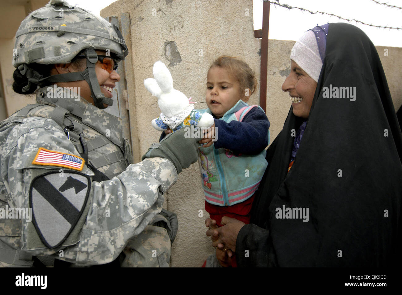 U.S. Army Spc. Deidre Olivas hands an Iraqi child waiting for medical treatment a stuffed animal during a combined medical mission in Quadria, Iraq, Dec. 7, 2007. Olivas is from Forward Support Troop, 1st Squadron, 7th Cavalry Regiment.  Tech. Sgt. William Greer Stock Photo