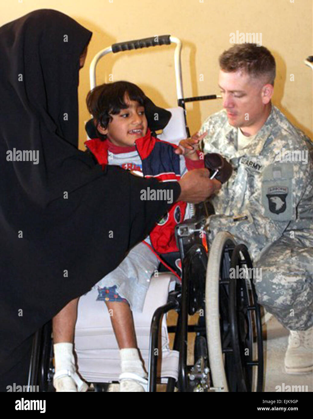 Army Sgt. Lonnie Todero, a medic with 1st Squadron, 33rd Cavalry, 3rd Brigade Combat Team, 101st Airborne Division Air Assault, makes adjustments to Zeanib Saad Al Amary's wheelchair Dec. 13, 2007, at Radwaniyah Palace Complex Civil-Military Operations Center in Iraq.  Sgt. 1st Class Kerensa Hardy, USA Stock Photo