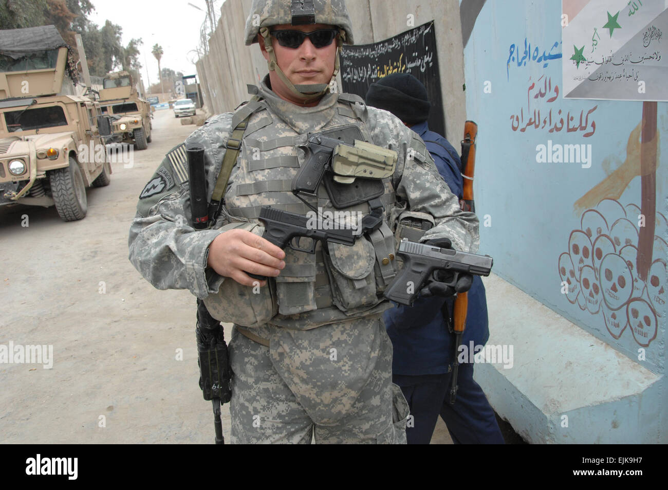 U.S. Army Staff Sgt. Terry Dahl, assigned to 9th Psychological Operations Battalion, holds a real .9-mm pistol in his right hand and a toy .9-mm pistol in his left hand at an Iraqi police station in Seddah, Iraq, Jan. 1, 2008, to demonstrate how similar the fake and real weapons look. Coalition forces are asking shop owners to stop selling the toys to children so they are not mistaken for insurgents.  Spc. Adam Sanders Stock Photo