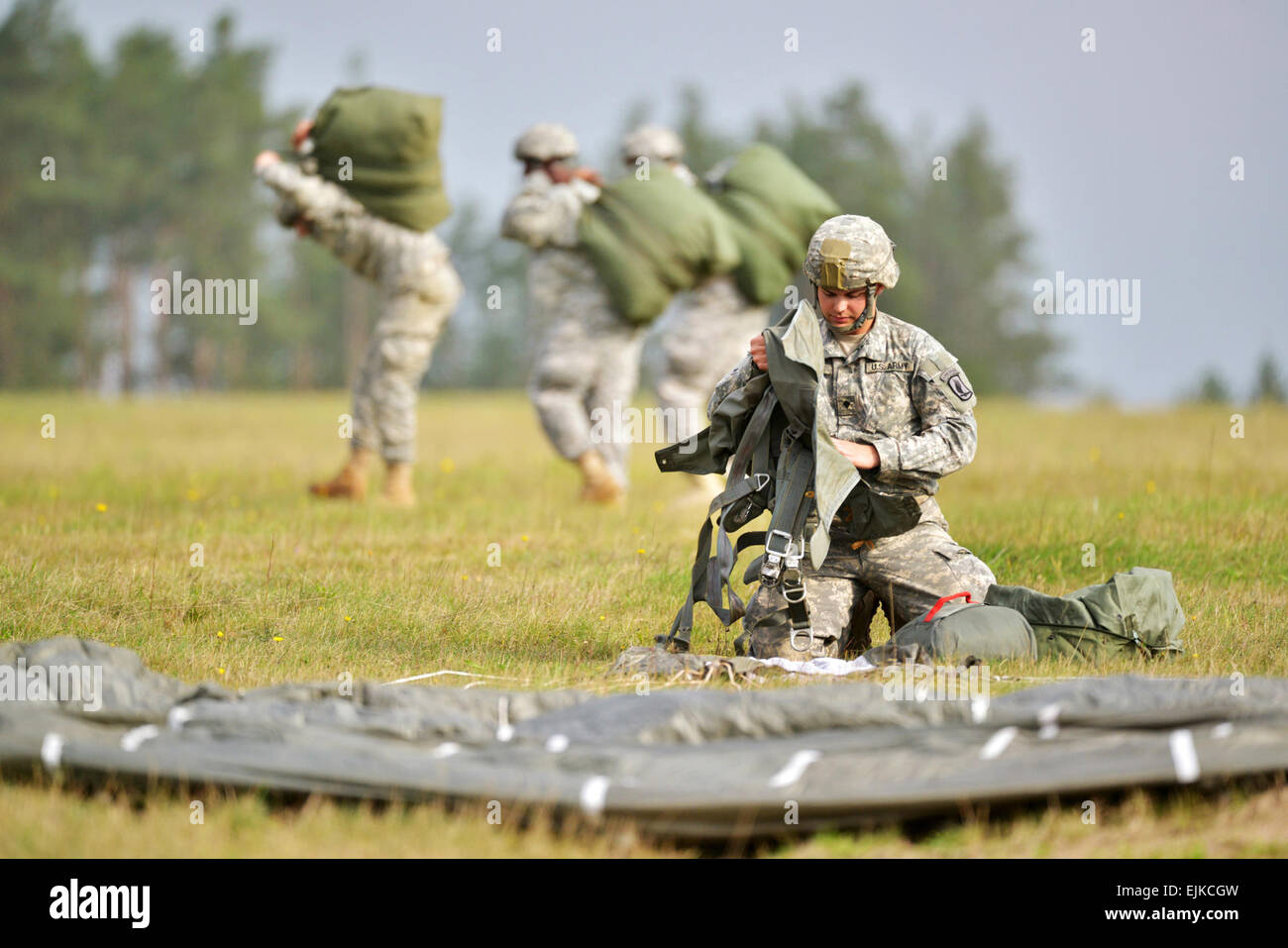 U.S. paratroopers, assigned to 91st Cavalry Regiment, 173rd Airborne Brigade, recover their T-11 advanced tactical parachute systems after landing. The Soldiers participated in the airborne exercise with the German 313th Airborne Battalion and 43rd Czech Airborne Battalion at the 7th Army Joint Multinational Training Command's Grafenwoehr Training Area, Germany, Oct. 1, 2014.   Spc. Gertrud Zach Stock Photo