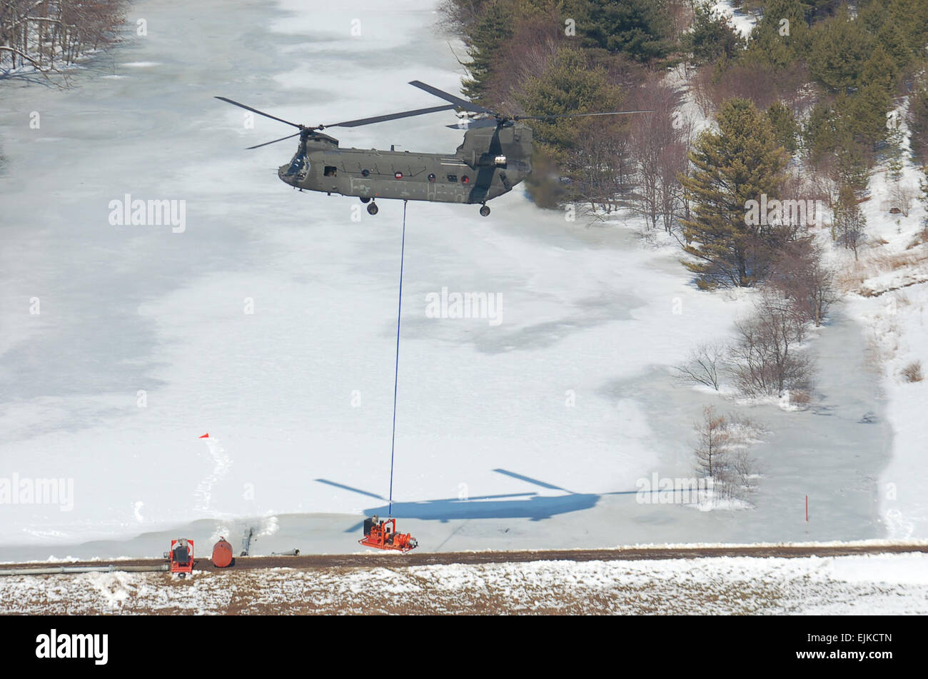 A Maryland Army National Guard CH-47D Chinook helicopter from Company B, 3rd Battalion, 126th Aviation Regiment, assists local authorities by hauling two giant pumps used to relieve pressure on a dam in the western Maryland town of Oakland on March 7. The dam had become dangerously full when a submerged outflow pipe had become clogged with sticks and mud placed by beavers. Stock Photo