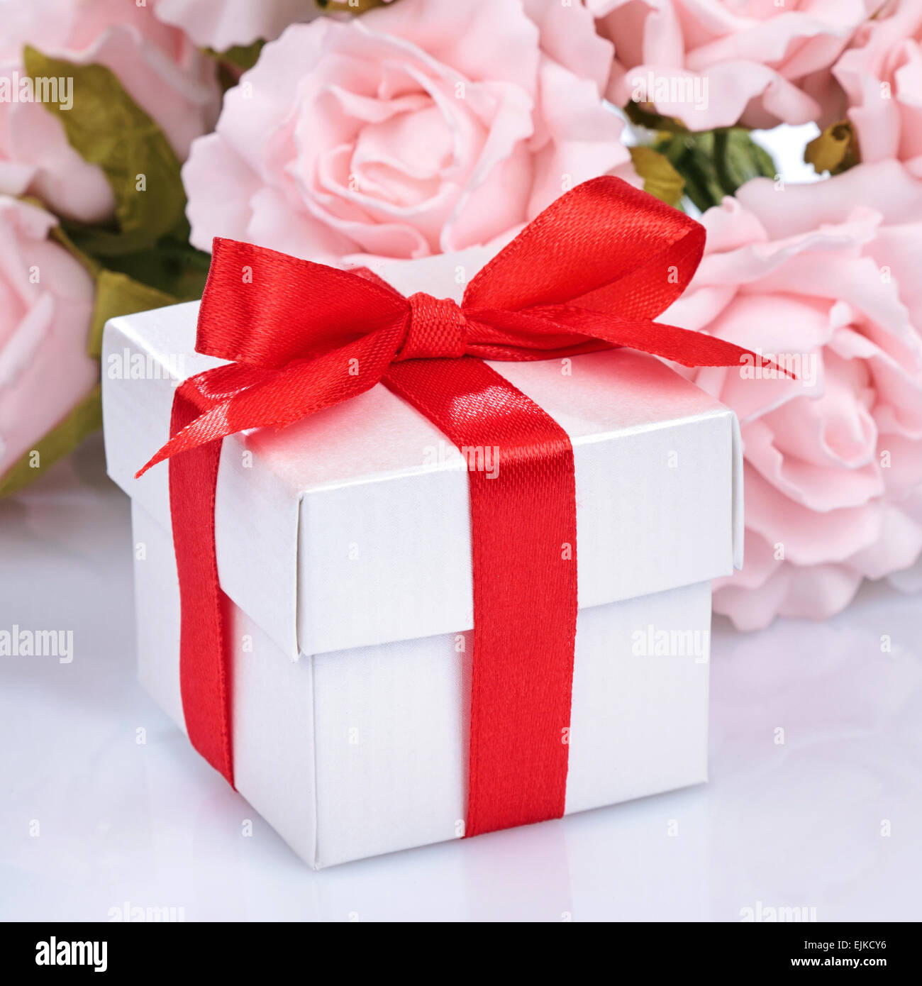 pink flowers and  gift box with red ribbon and bow on a white ba Stock Photo
