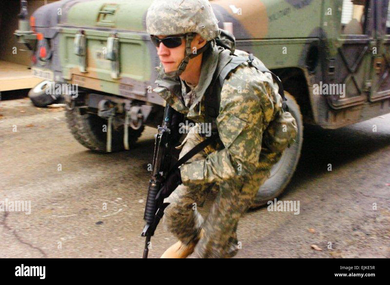 Spc. Dustin Schultz, a Seymour, Ind., native and military policeman with the 384th Military Police Company, runs from one vehicle to another under enemy fire during an enemy ambush to ensure all State Department officials have been safely loaded into vehicles for evacuation.  The 384th Soldiers acted as security forces for the State Department as they went through Foreign Service Institute Training at the Muscatatuck Urban Training Center Feb 13-18. Stock Photo