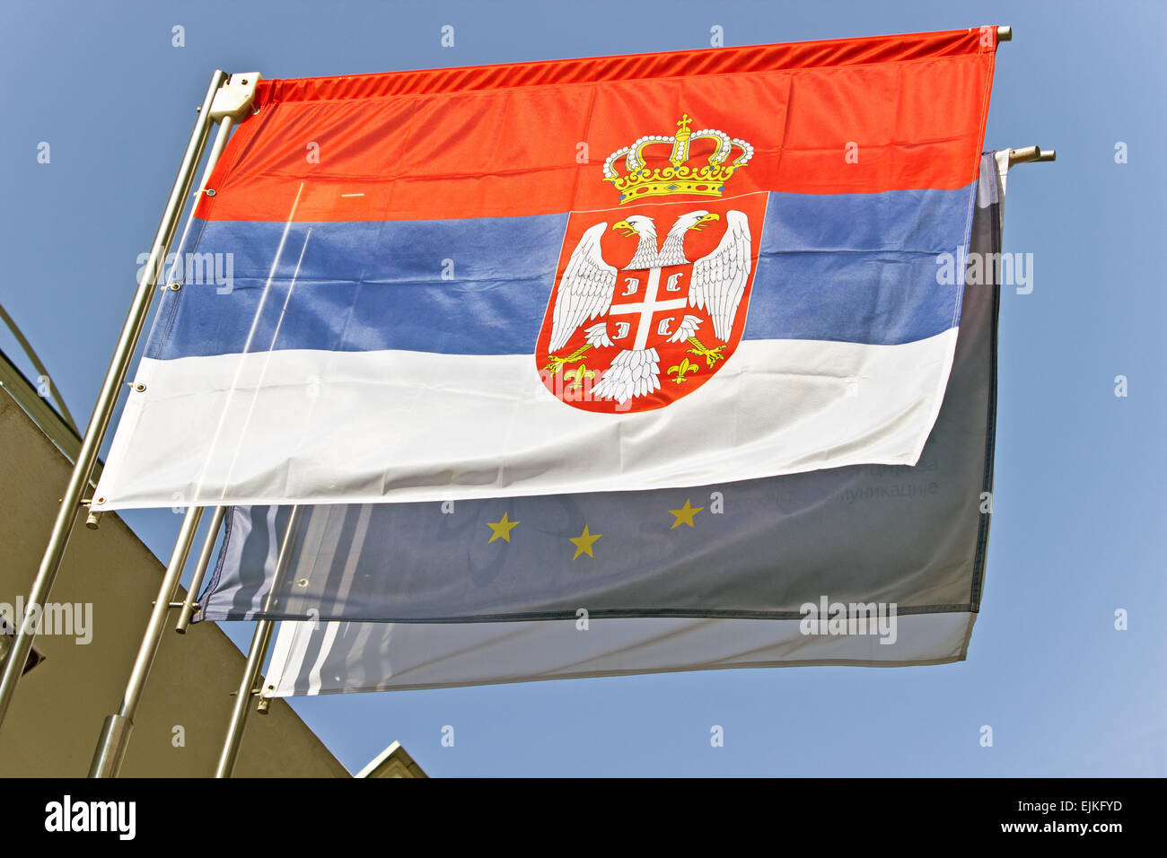 Serbian flag waving with European Union flag over sky Stock Photo