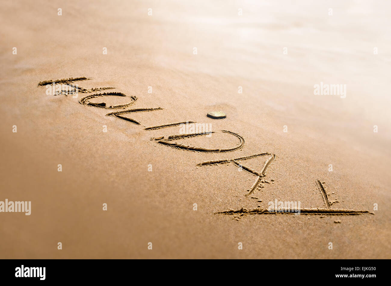 Holiday word written on the sand bright back light effect Stock Photo