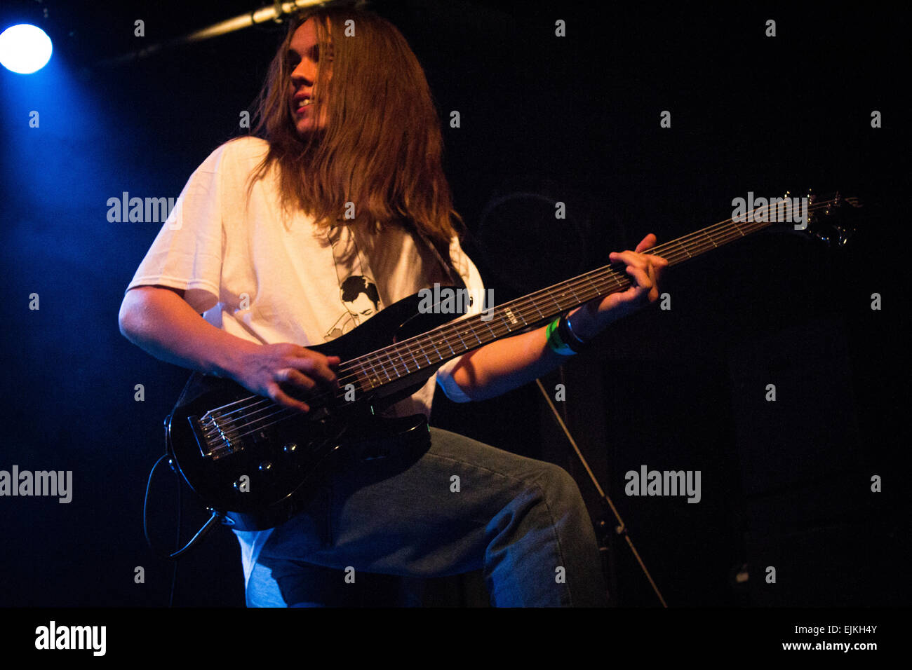 Man with long hair in a band playing a five string bass guitar Stock Photo  - Alamy