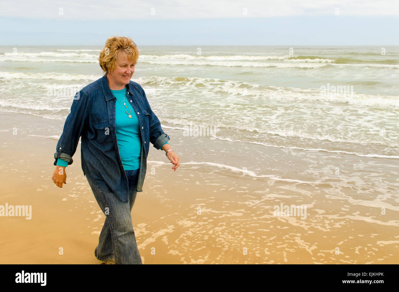 Senior woman walking on the beach Stock Photo