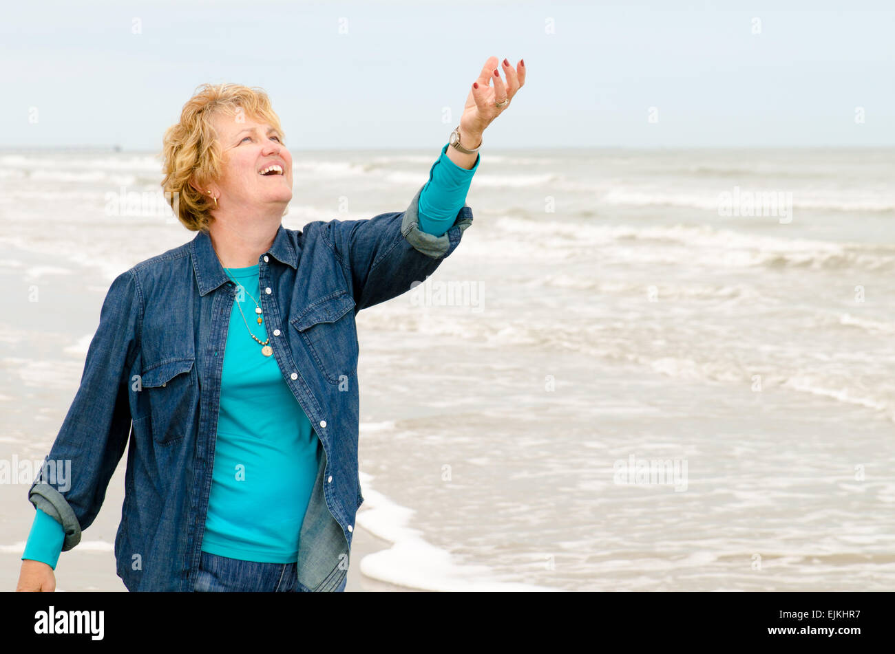 Woman on the beach with her arm outstretched upward Stock Photo