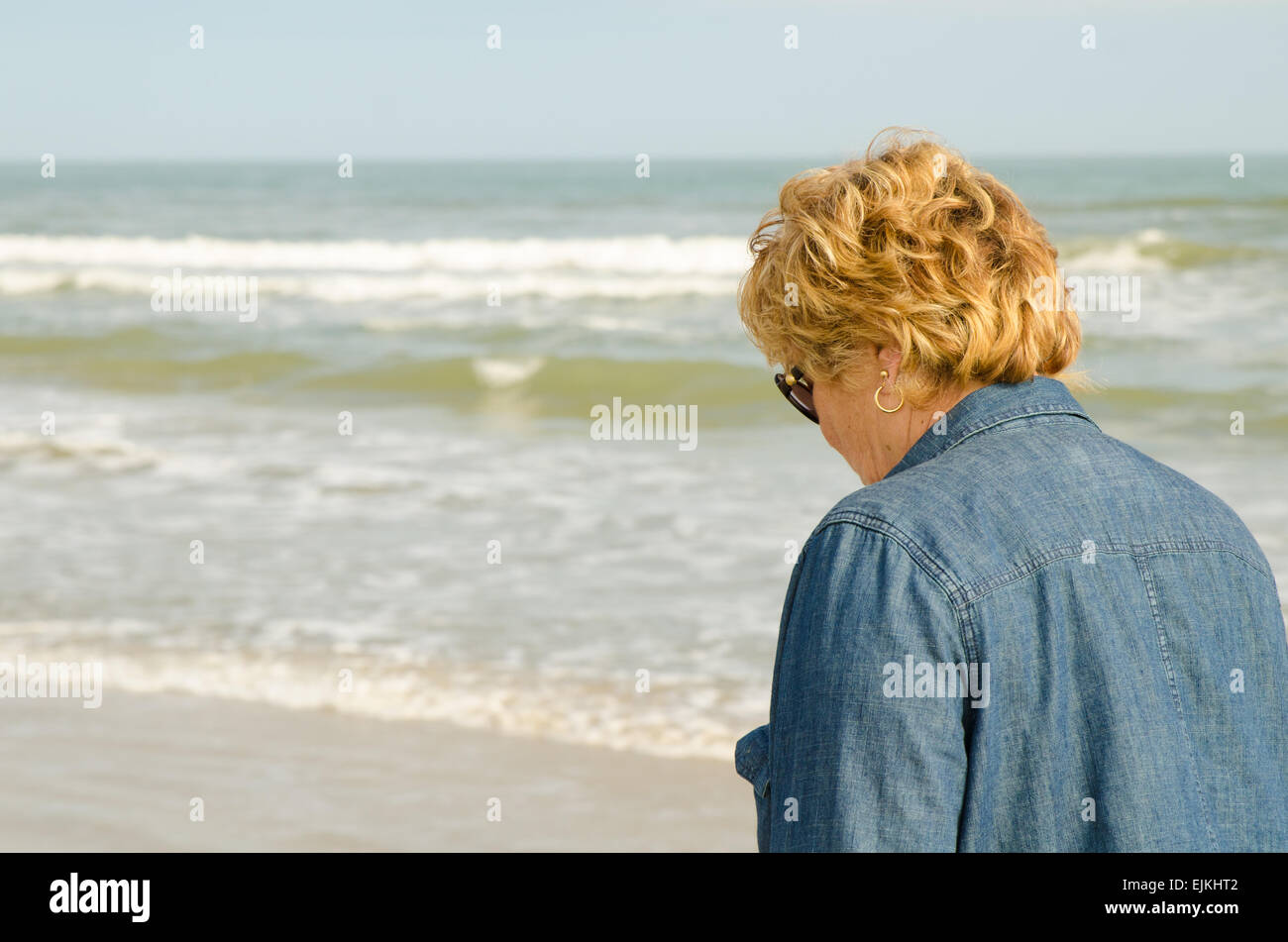 Senior woman in her 60s walking on the beach Stock Photo