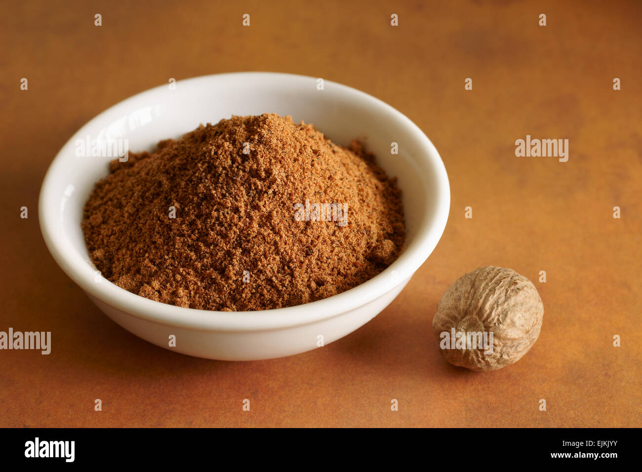 Whole and ground nutmeg a fragrant spice from the fruit Myristica fragrans indigenous to the Banda Islands of Indonesia Stock Photo