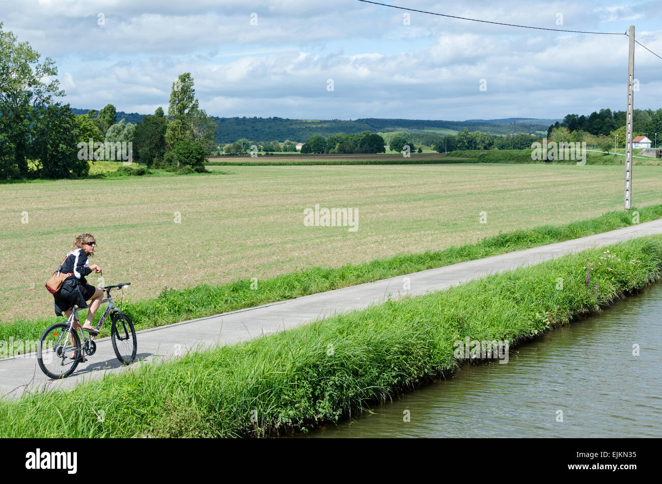 A woman pauses while biking on the Voie Verte running along the Canal du Centre near Rully in Burgundy, France. Stock Photo