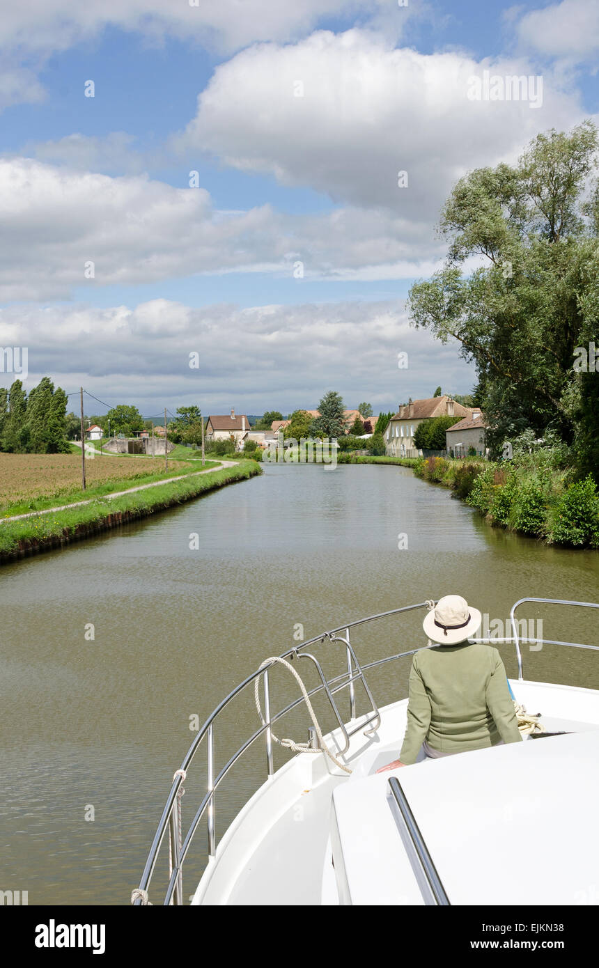 A woman admires the view from the bow of a pleasure boat on the Canal du Centre, Burgundy, France. Stock Photo