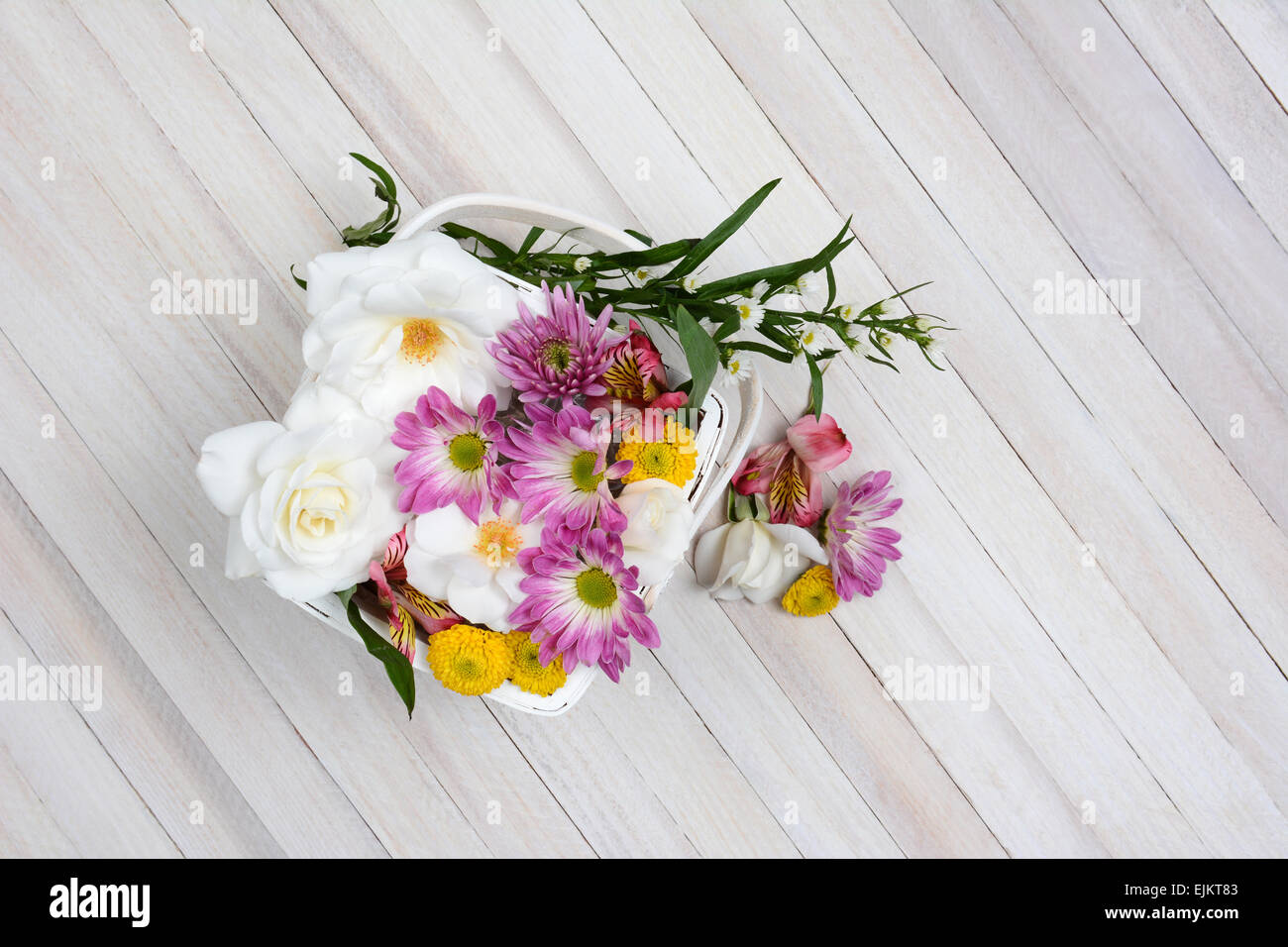 Basket of Spring flowers on a wood table. Overhead shot in horizontal format with copy space. Stock Photo