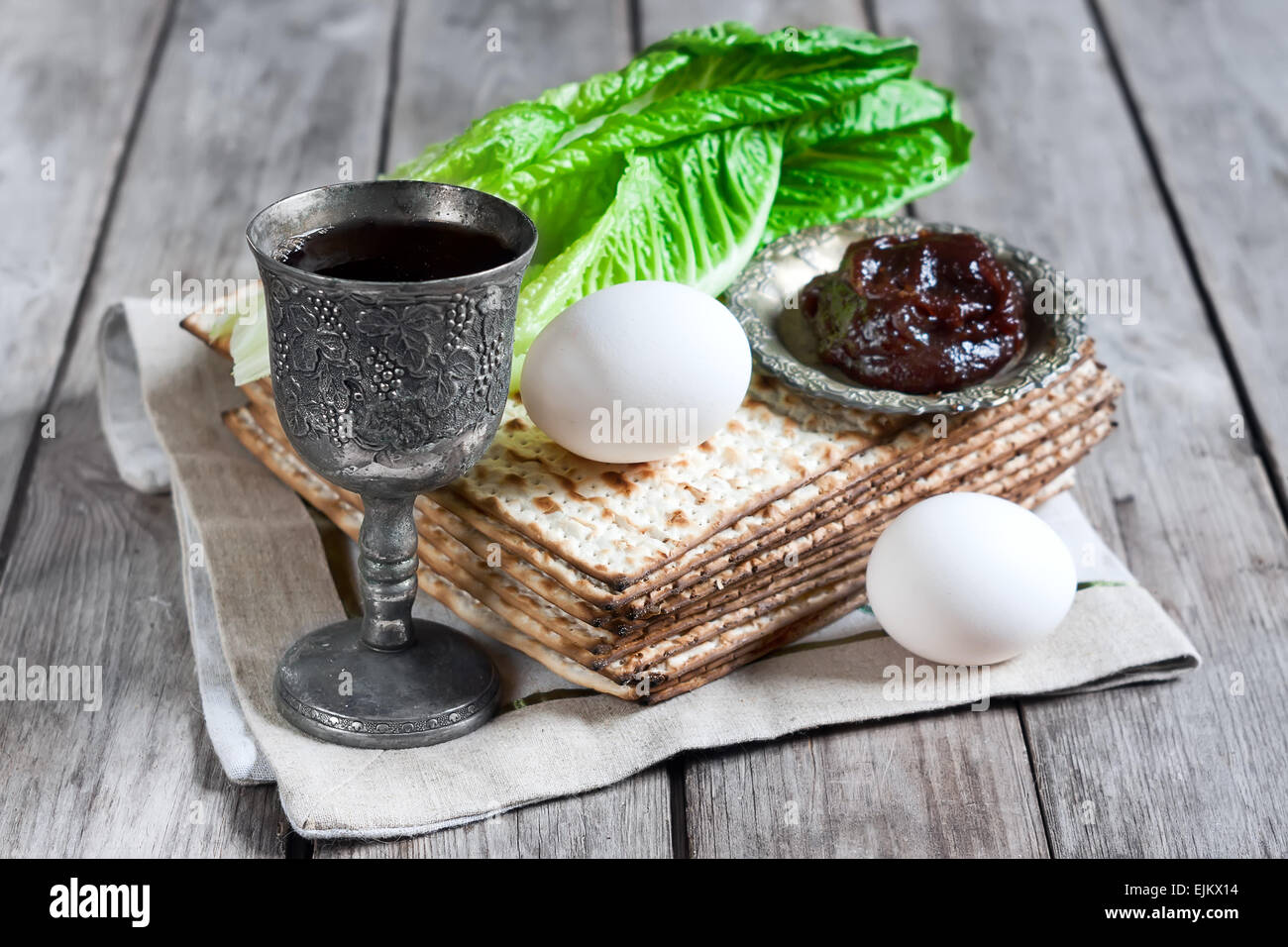 Wine, egg, bitter salad leaves, matzot and haroset - traditional jewish passover celebration elements. Stock Photo