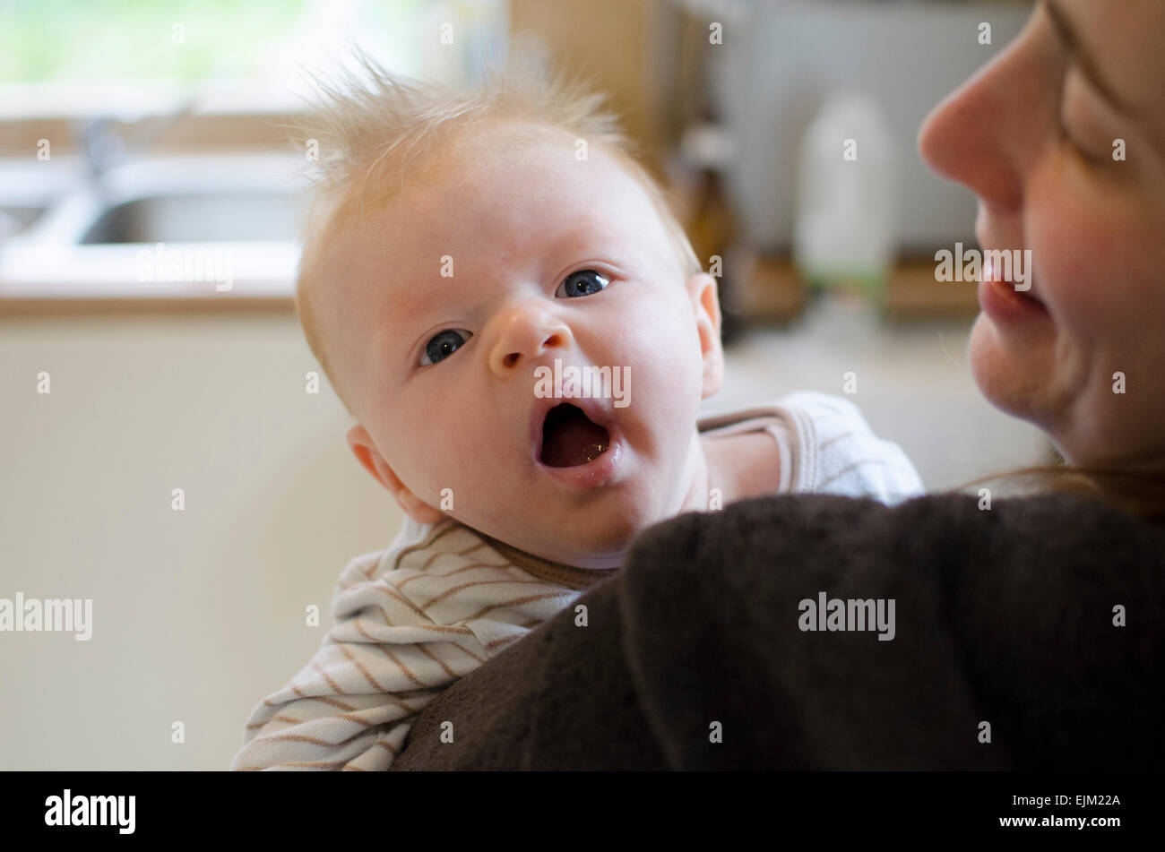 Yawning 14-week-old baby boy on his mother's shoulder. Stock Photo