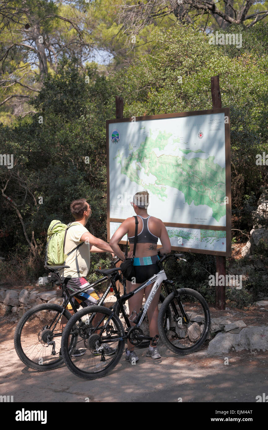 Cyclists look at Map of Mljet Croatia Tourists on hired bikes in Mljet National Park Stock Photo