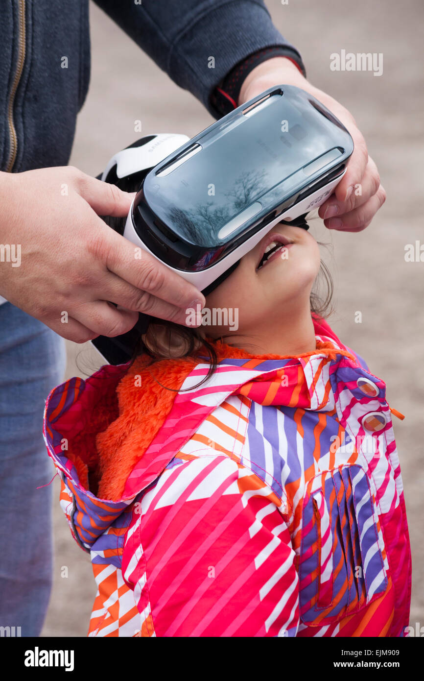 Helping young girl watching film on Samsung Gear VR virtual reality headset. Stock Photo
