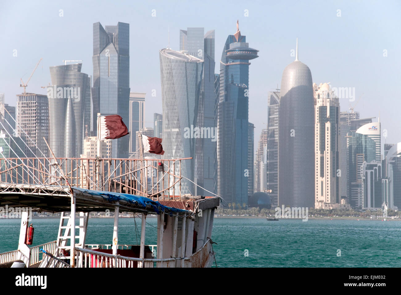 Qatari flags flap on a dhow boat in the Arabian Gulf with the skyline of Doha in the background. Stock Photo