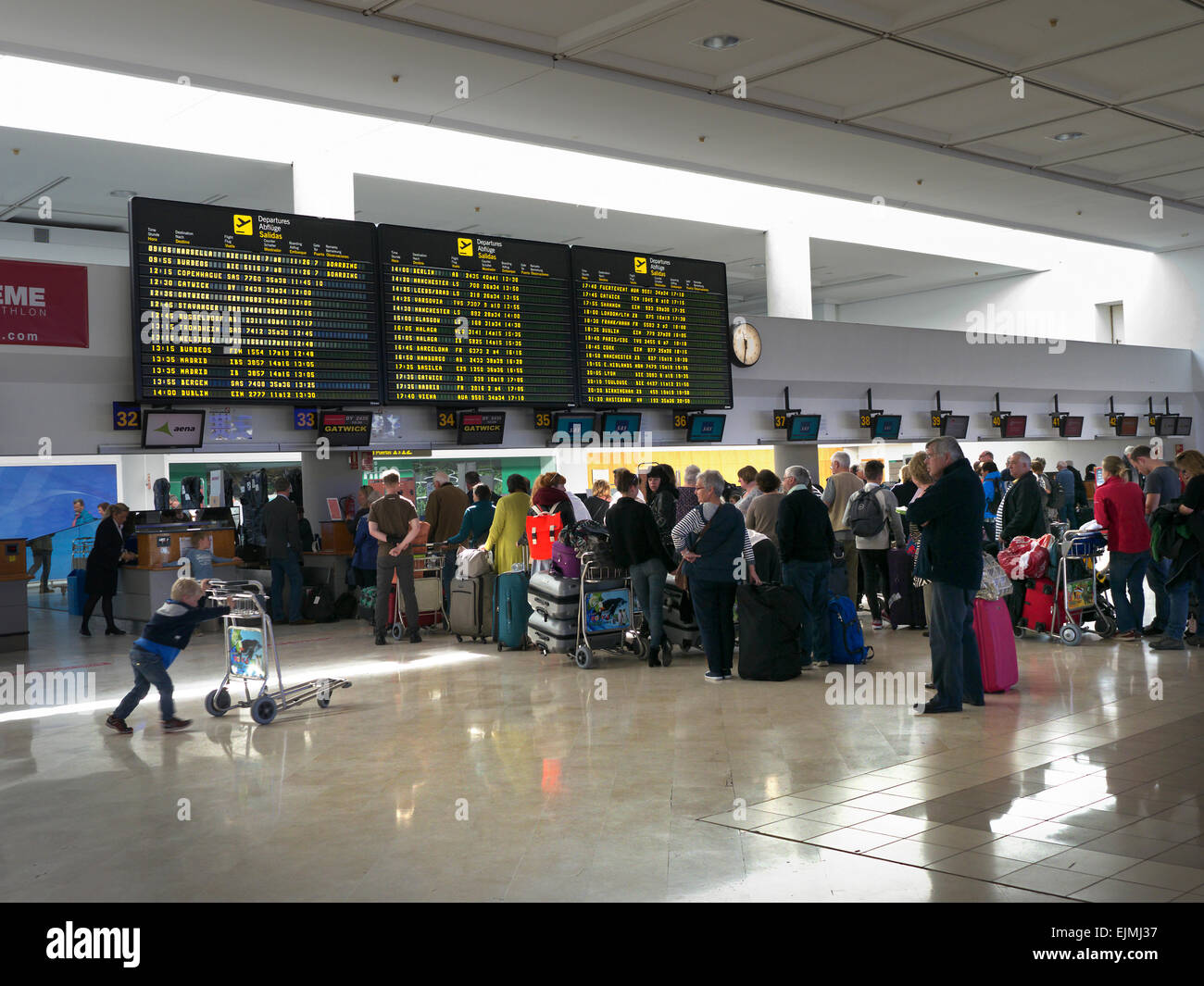 Airport Queue of charter flight passengers and luggage wait at airport terminal to check in baggage to their flight Spain Stock Photo