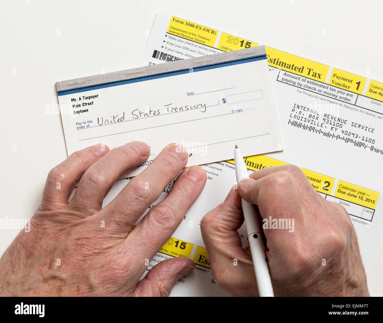 Male caucasian hands writing check to Internal revenue service IRS form 1040-ES for payment of estimated taxes in 2015 Stock Photo