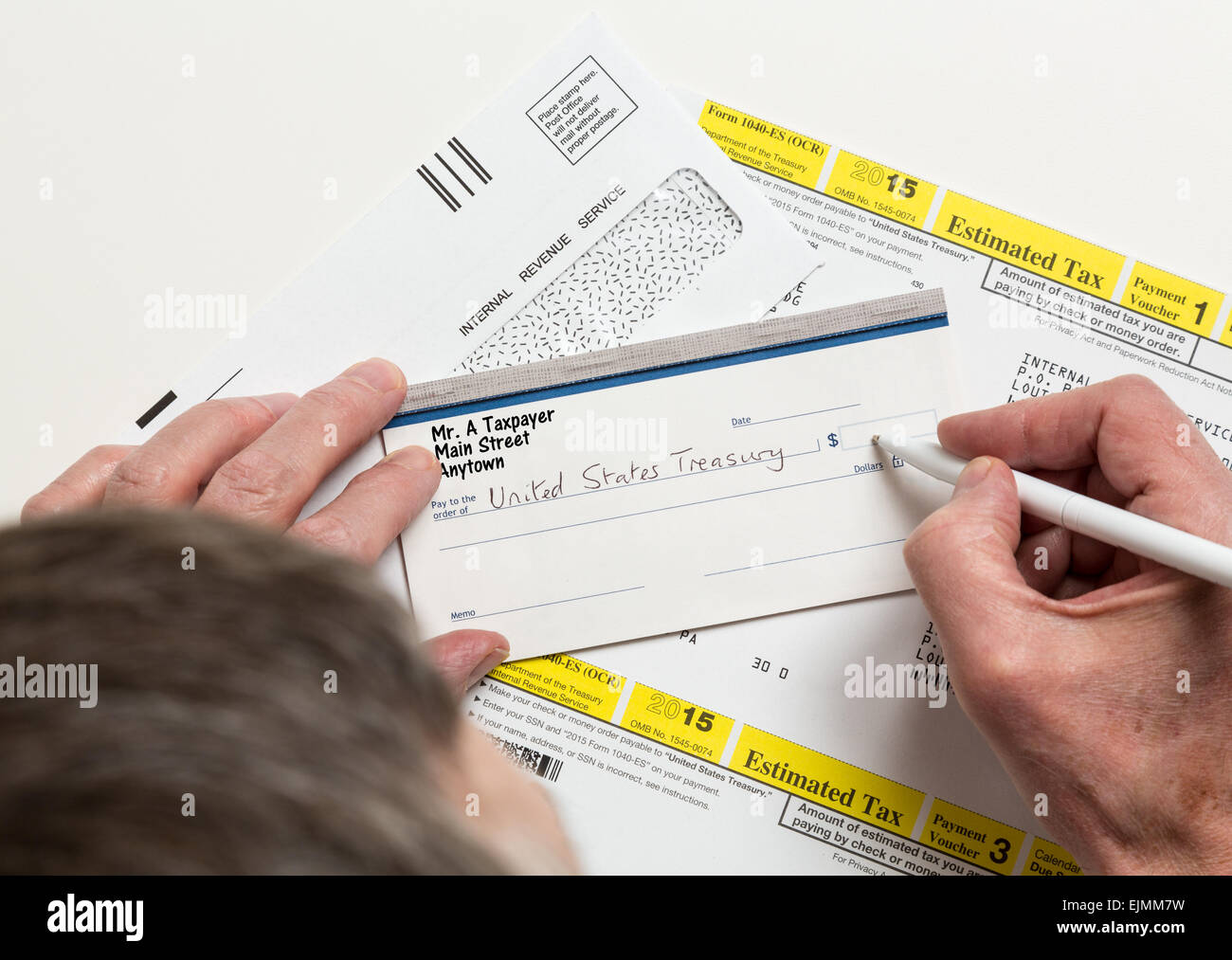 Male caucasian hands writing check to Internal revenue service IRS form 1040-ES for payment of estimated taxes in 2015 Stock Photo