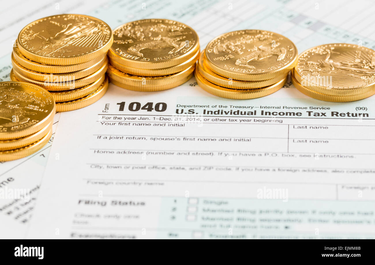 Solid gold eagle coins on USA tax form 1040 for year 2014  illustrating payment of taxes on forms for the IRS Stock Photo