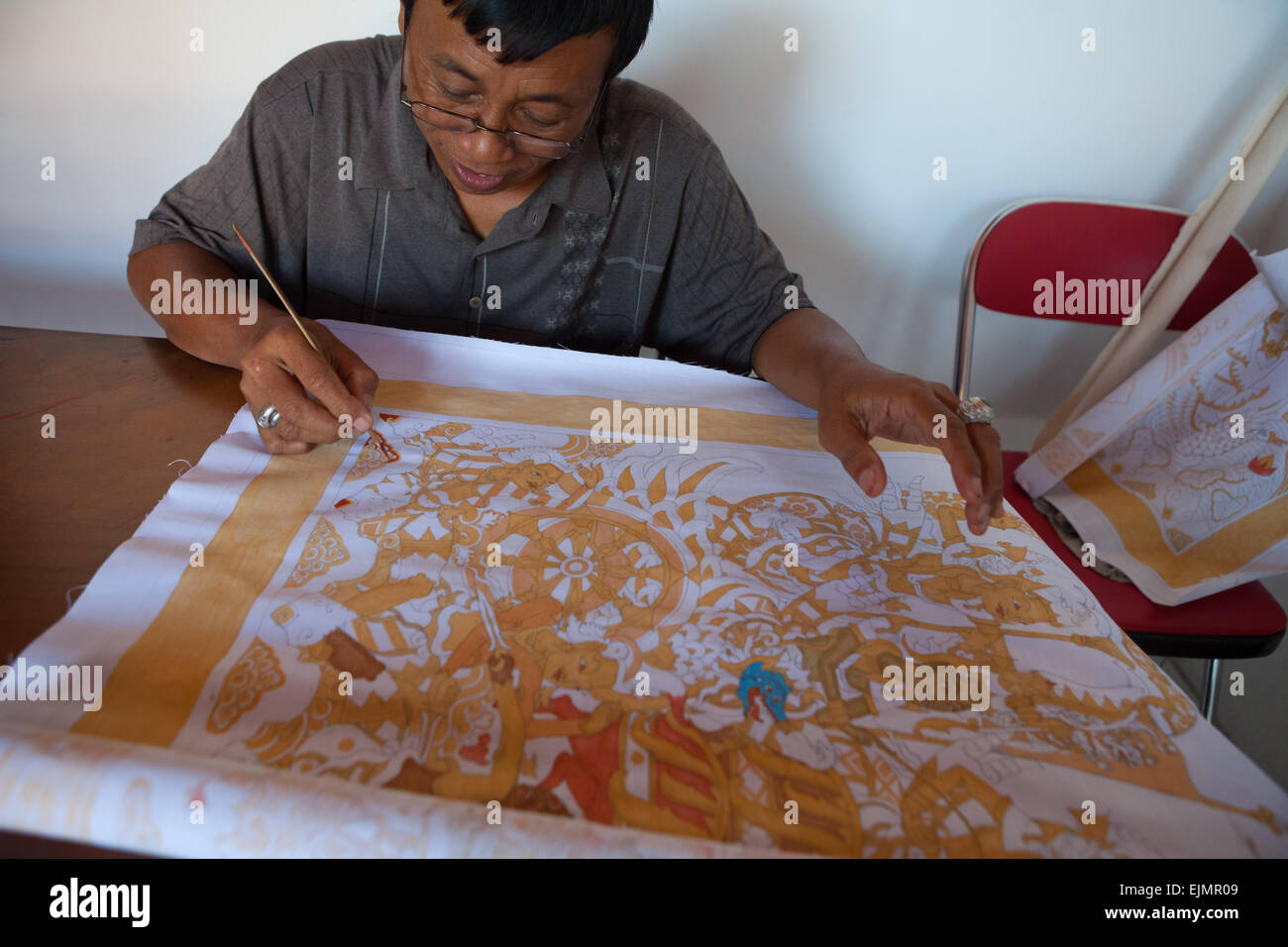 An artist painting his artwork of old Kamasan-style painting in Klungkung, Bali, Indonesia. Stock Photo