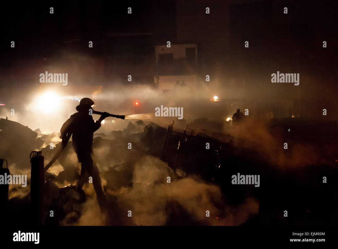Jakarta firefighters brigade work between debris after a battle in a dense neighborhood. Archival image. Stock Photo