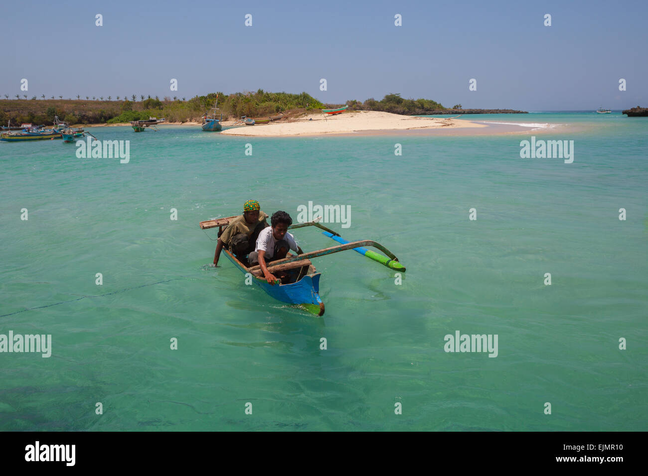 People rowing a small boat by hands on the coastal water of Pero, a fishing village in Kodi, Southwest Sumba, East Nusa Tenggara, Indonesia. Stock Photo