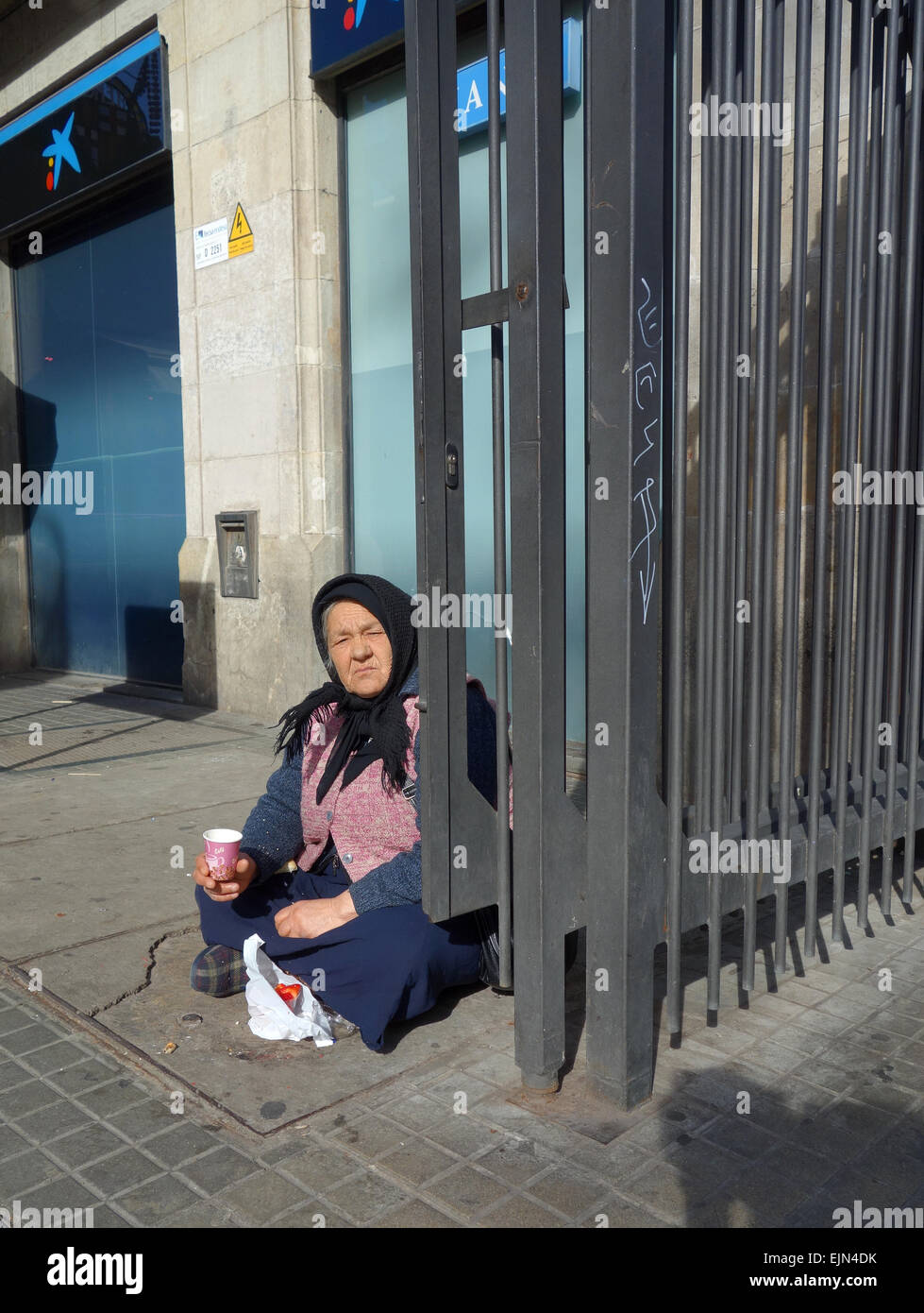 Old woman sitting on ground, begging outside La Boqueria market on Las Ramblas in Barcelona, Catalonia, Spain Stock Photo