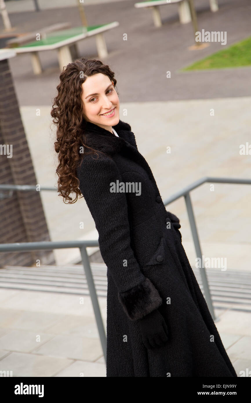 portrait of a young woman wearing a black coat and gloves Stock Photo