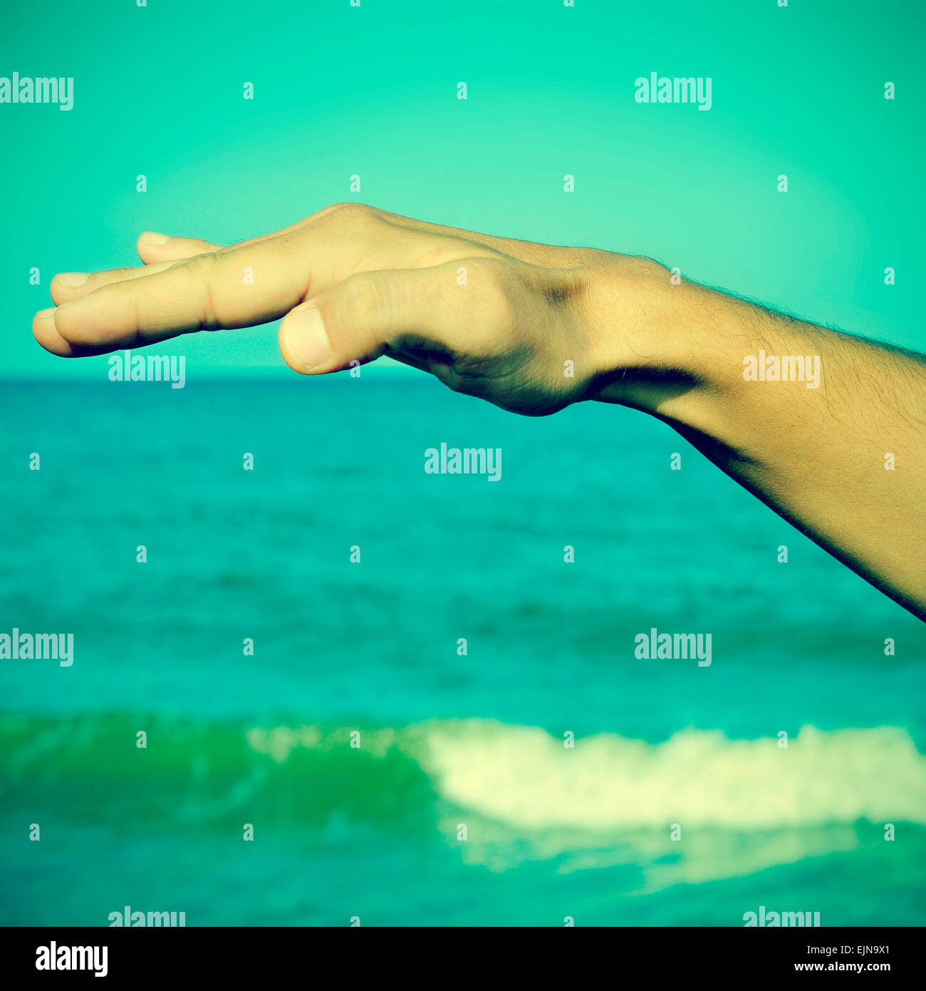 picture of a man waving free his hand in the air with the ocean at the background, with a retro effect Stock Photo