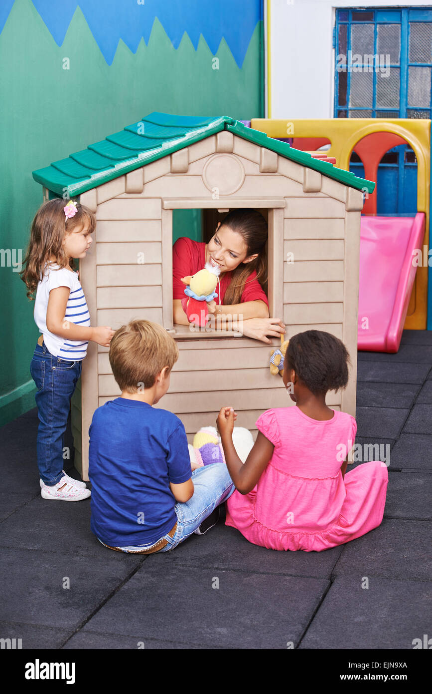 Educator playing theater for children in a playhouse in preschool Stock