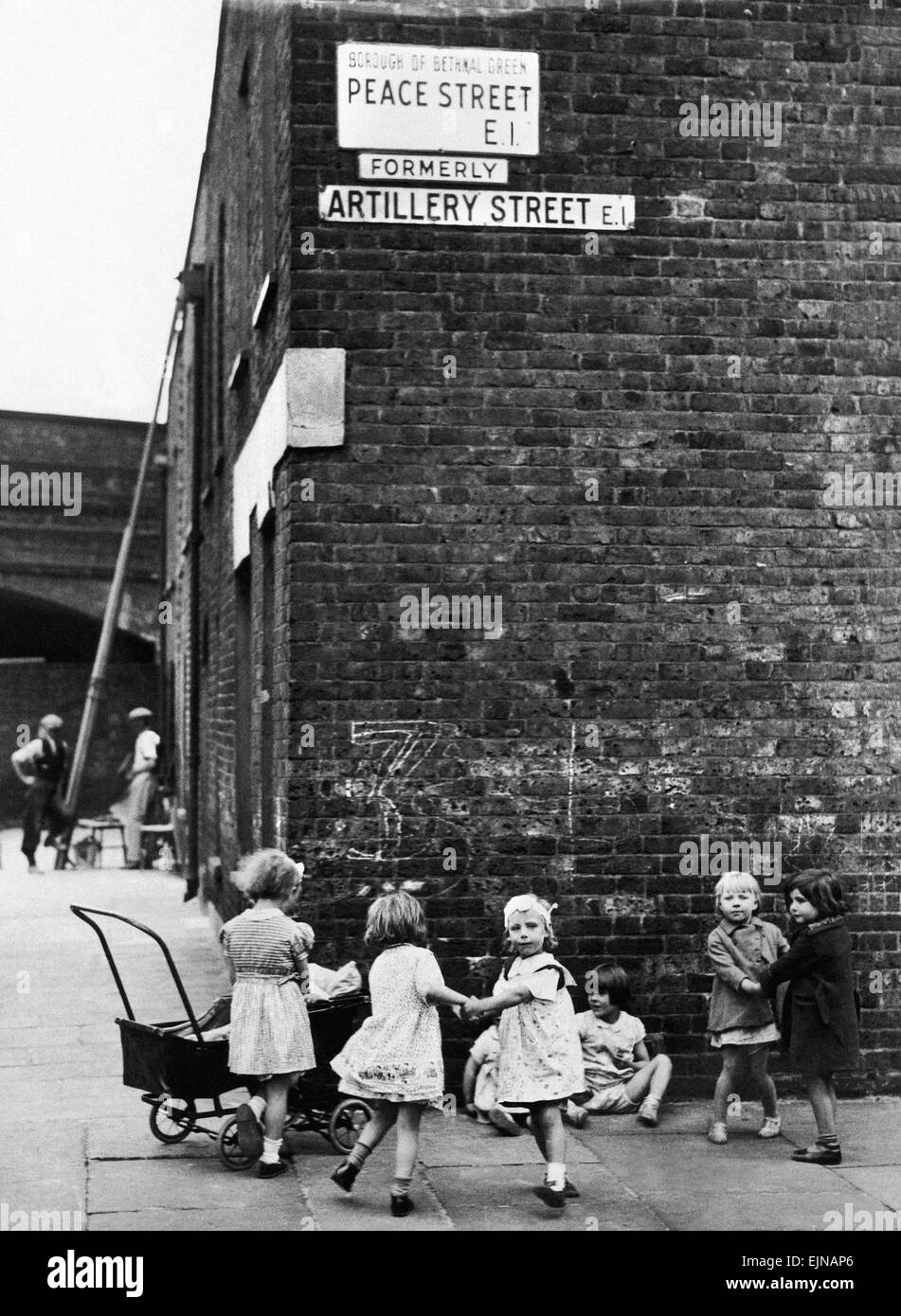 Young girls playing mums with their dolls and toy prams on the corner of Peace Street, formerly Artillery Street, in Bethnal Green, East London. 24th July 1939. Stock Photo