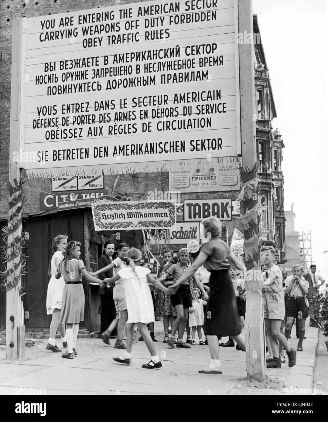 Berlin a city divided. Childrens party at the sector boundary Berlin 15th August 1953. This picture was taken from the eastern part of Friedrich strasse. It shows children playing in the vicinity of the sector boundary sign. Only a few months earlier in June during the workersÕ revolt in East Germany, American and Soviet tanks stood opposite each other in the Friedrich Strasse, creating a credible threat of force at the Allies sector line, Checkpoint Charlie. From that time on, the border crossing at Checkpoint Charlie symbolised the collision of two world systems of Democracy and Communism. F Stock Photo